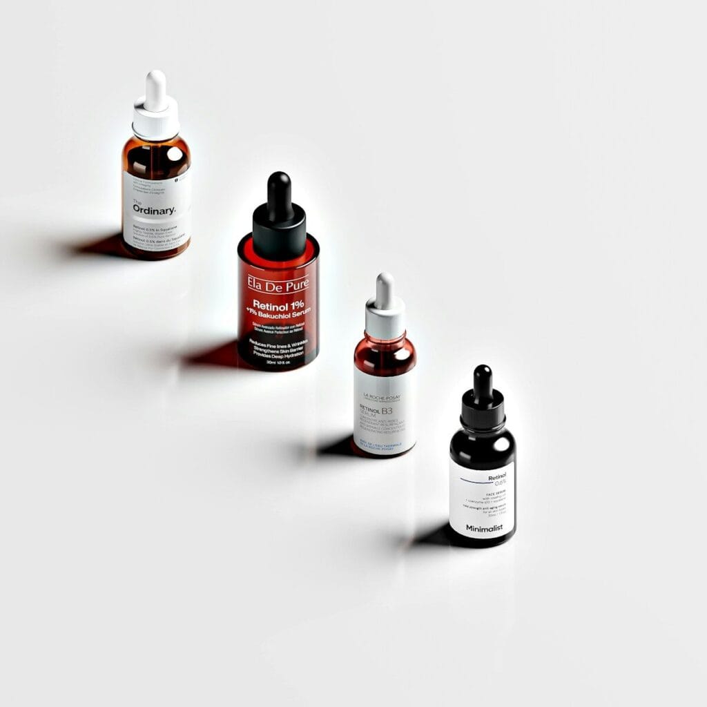 Four glass dropper bottles of skincare serum arranged in a diagonal line